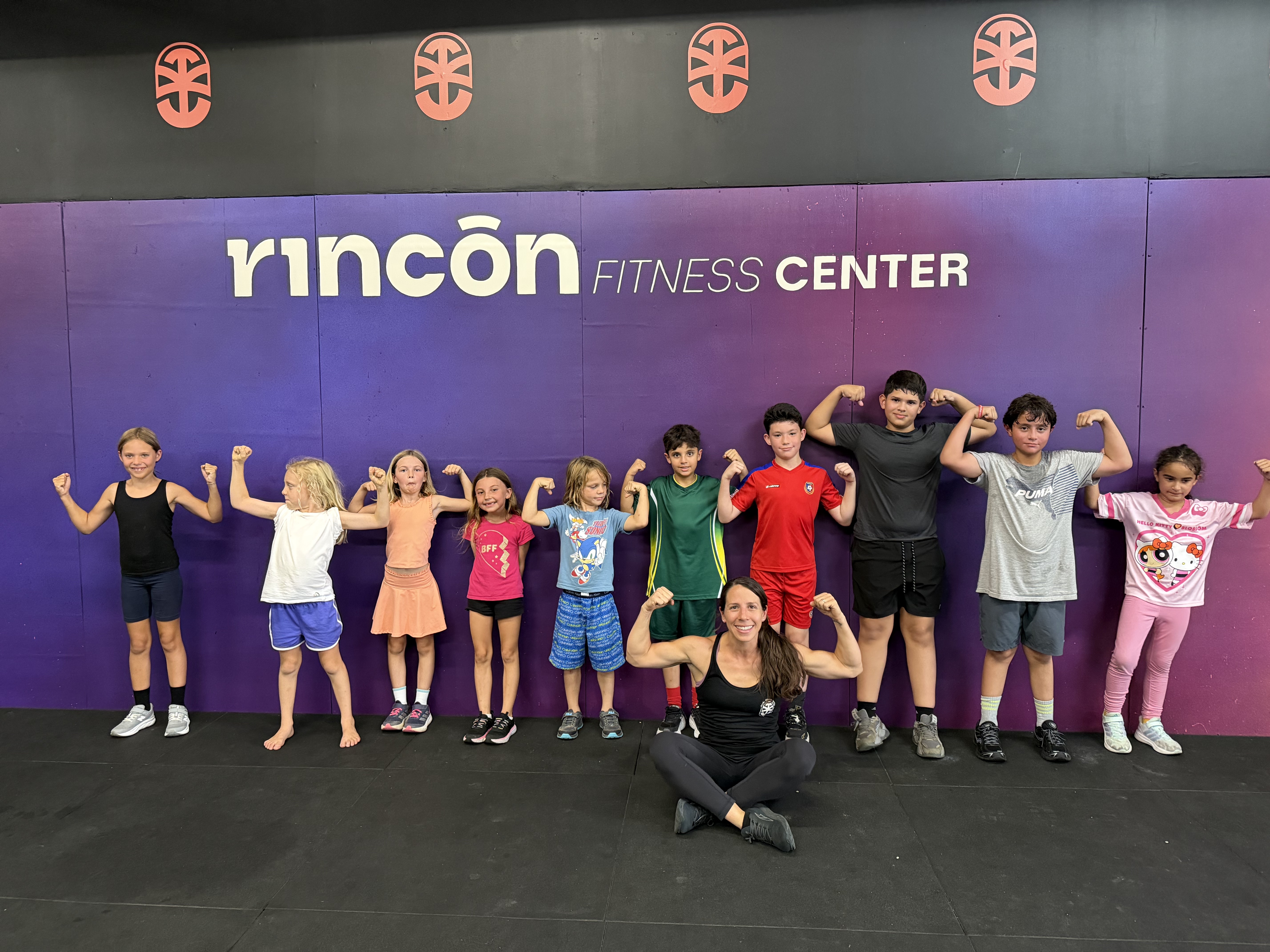 Ages 7-10 group flexing after class with their coach